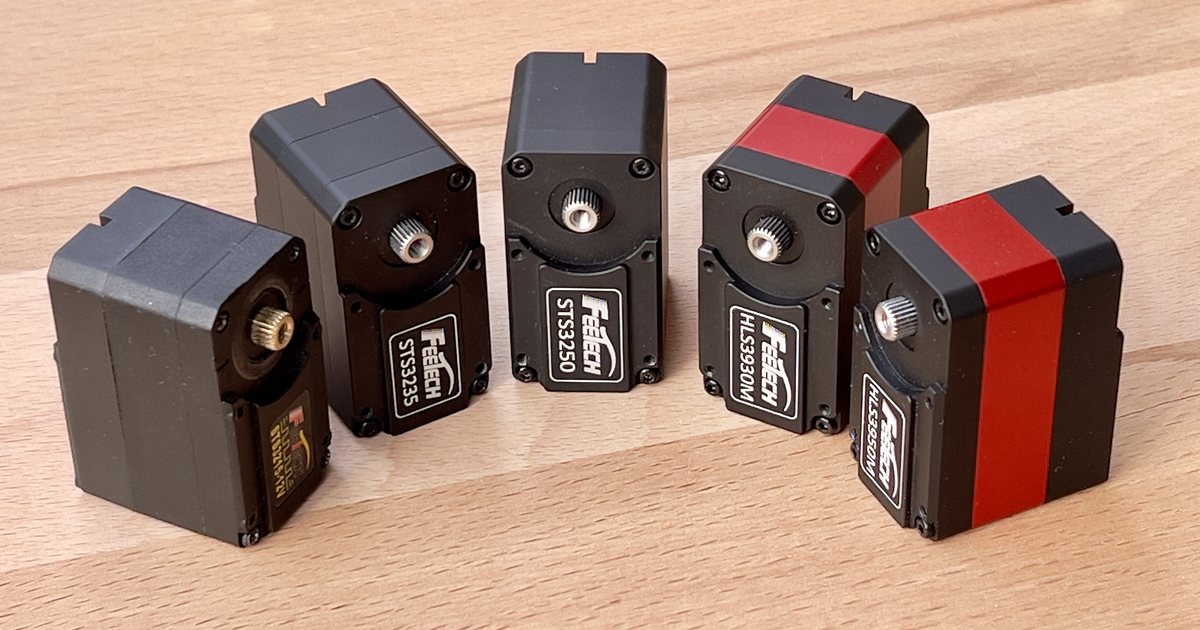 Five Feetech smart serial servos (STS3215, STS3235, STS3250, HLS3930M, HLS3950M) lined up on a workbench