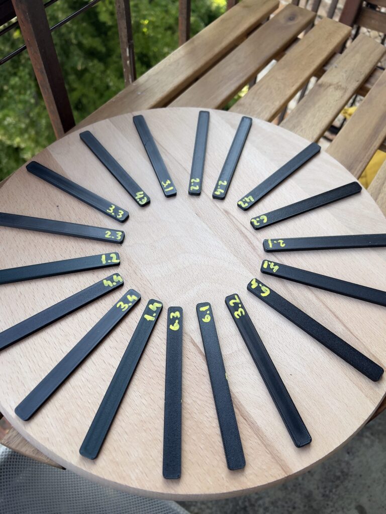 Numbered 3D printed bending test specimens arranged on a round wooden board before testing
